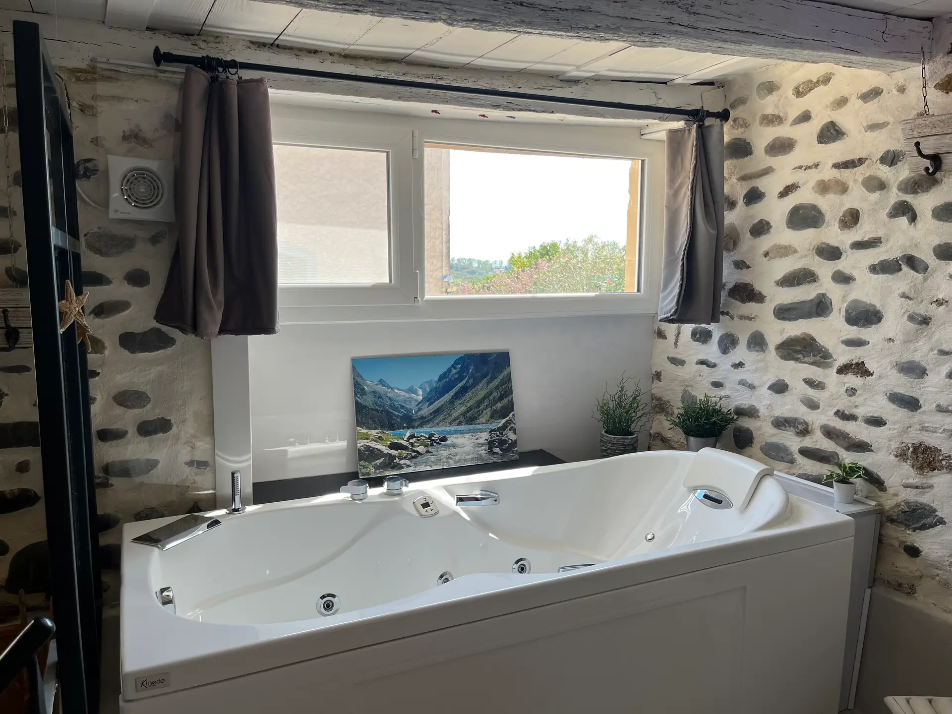 La baignoire balnéo du gîte, jets apparents, devant une fenêtre ouverte sur la campagne béarnaise.