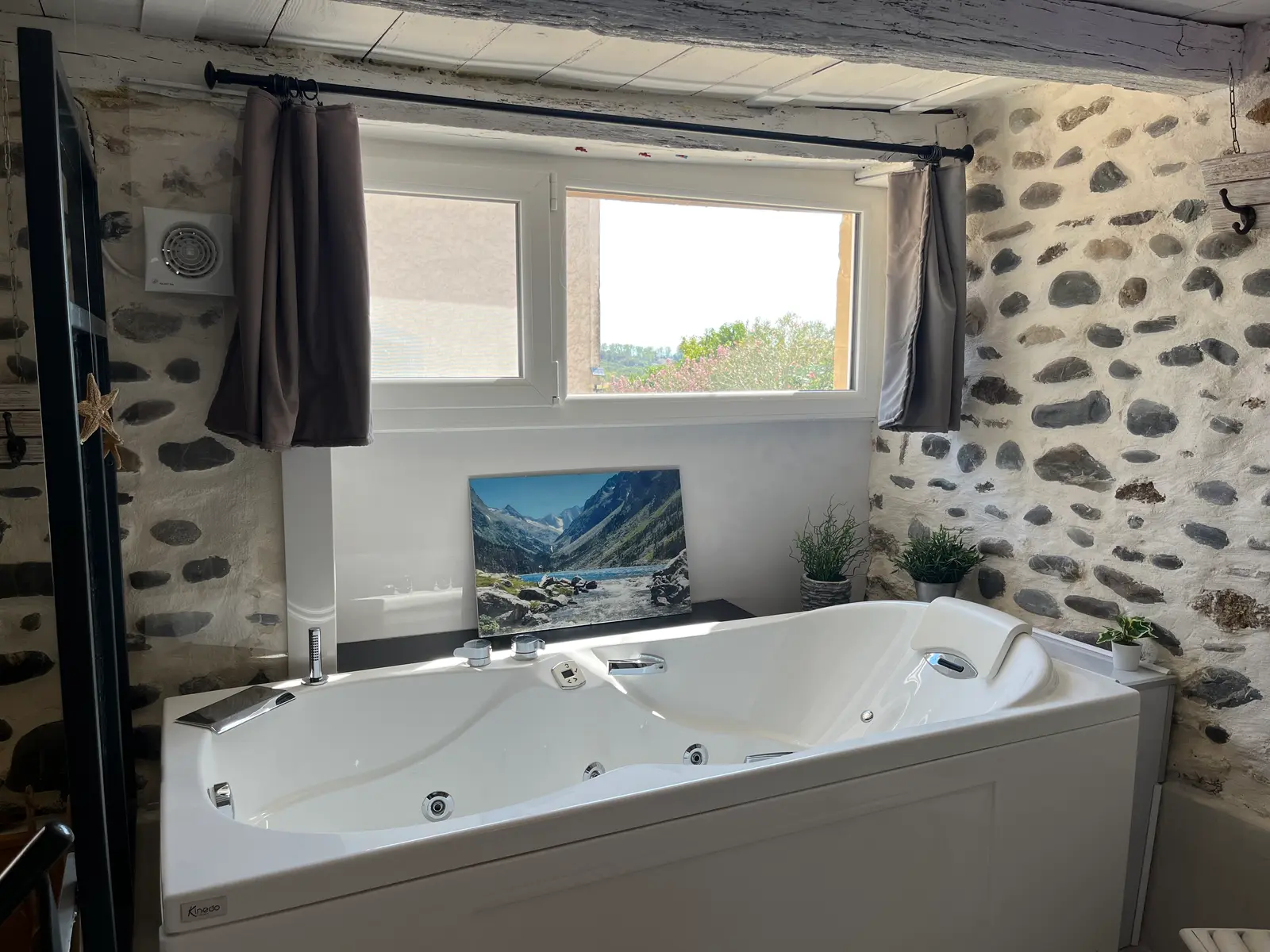 La baignoire balnéo, jets apparents et appuie-tête, devant une fenêtre ouverte sur la campagne.