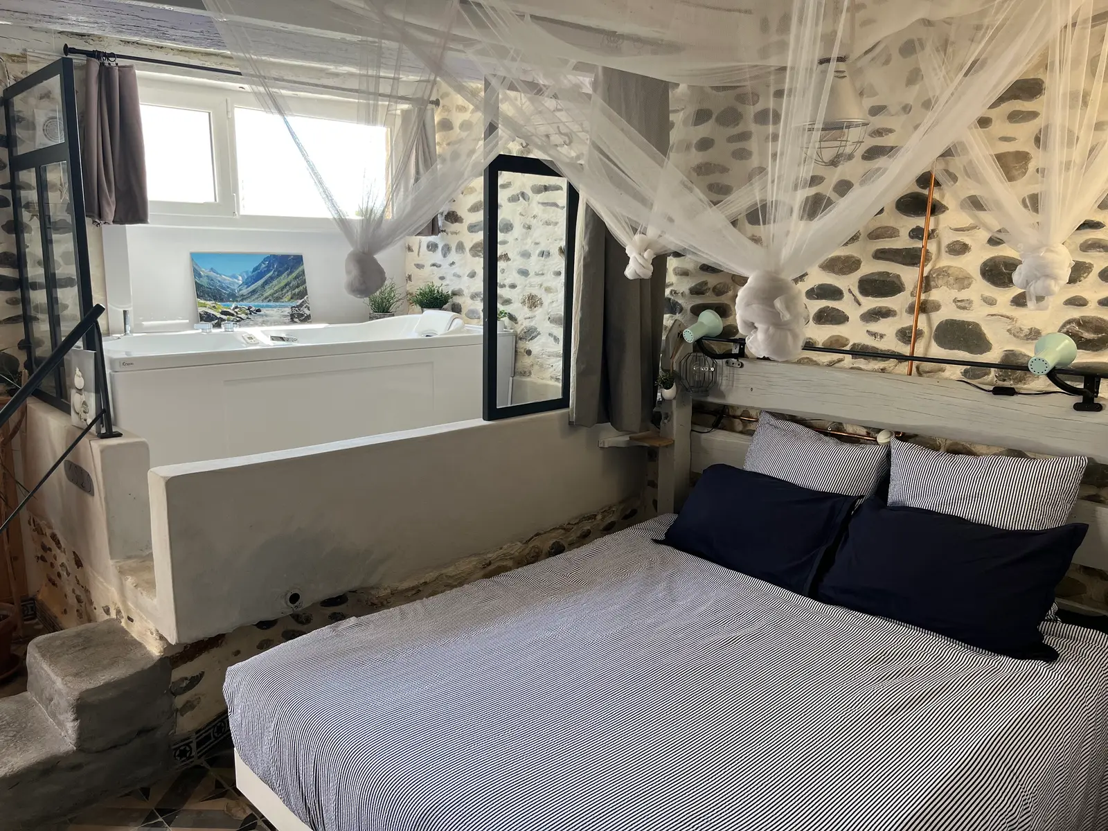 Le lit sous sa moustiquaire, et la baignoire balnéo installée sur une plateforme surélevée derrière.
