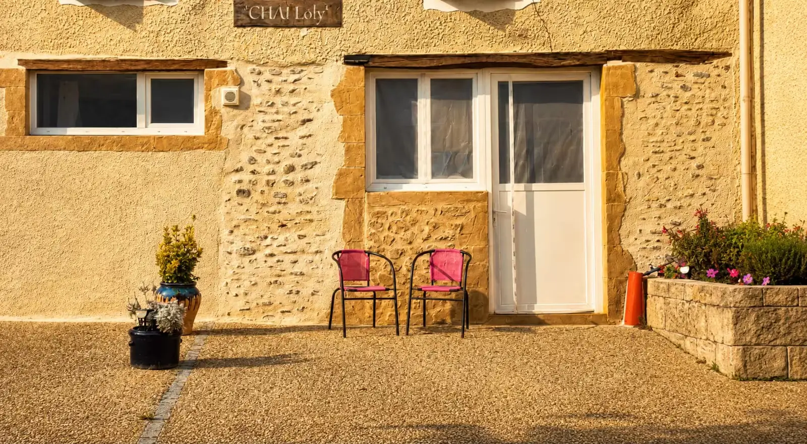 La façade du corps de ferme avec l’enseigne en bois « Chai Loly » au-dessus de la porte d’entrée du gîte.