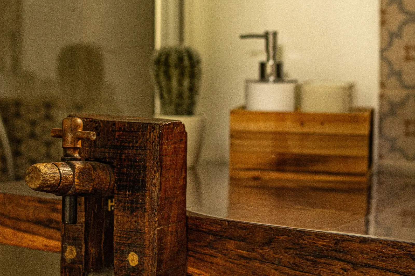 Détail de la salle d’eau : poutre de bois ancien et distributeur de savon posé sur le plan.
